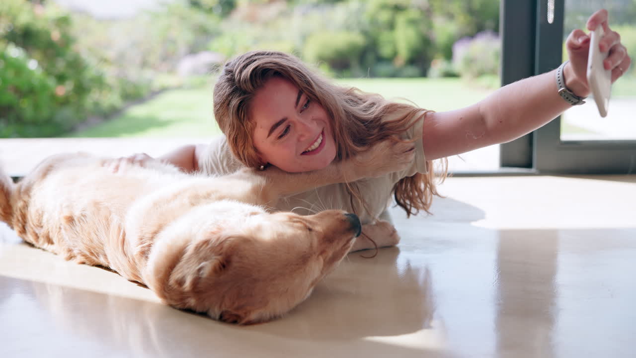 Woman taking selfie with her golden retriever dog at home