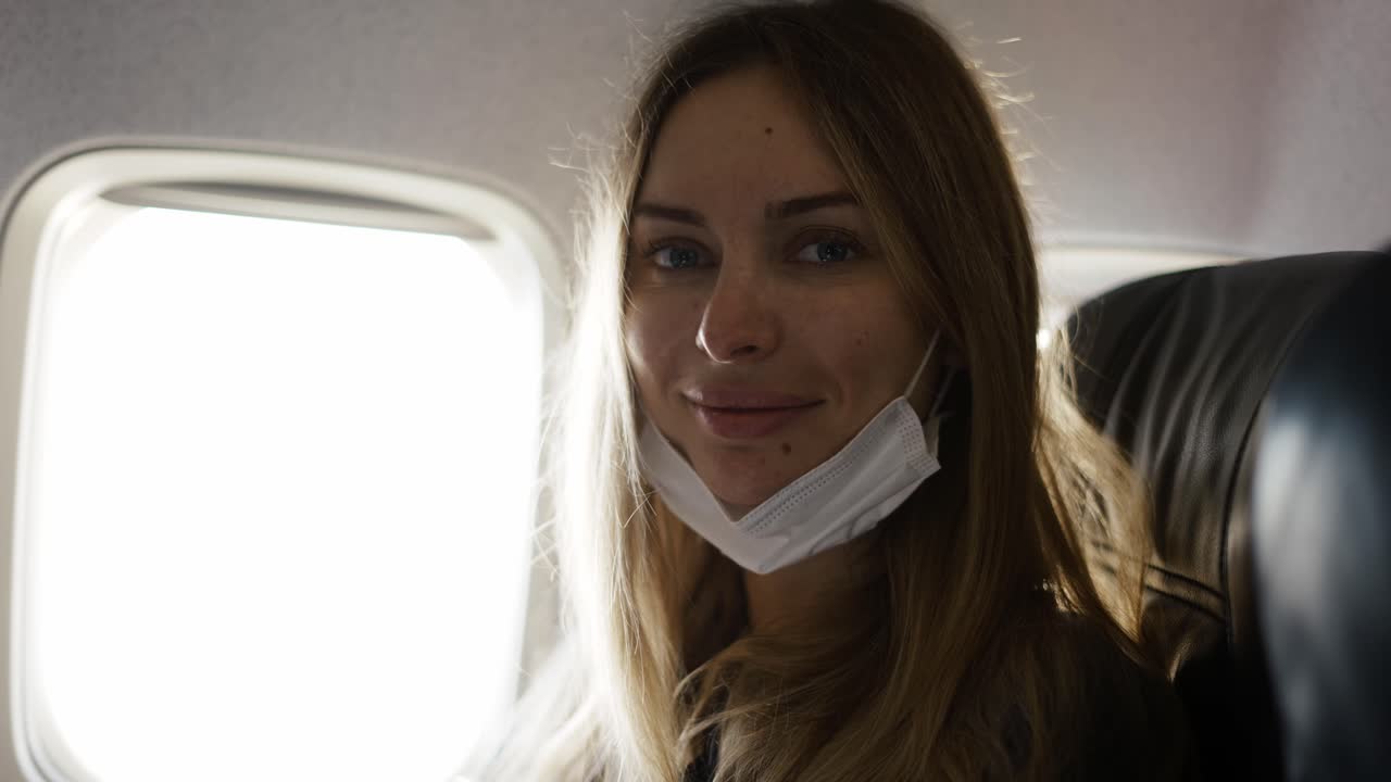 Retrato de mulher tirando a máscara no avião olhando para a câmera