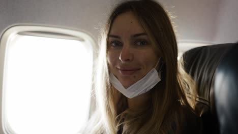 Portrait-of-woman-taking-off-mask-on-plane-looking-to-the-camera