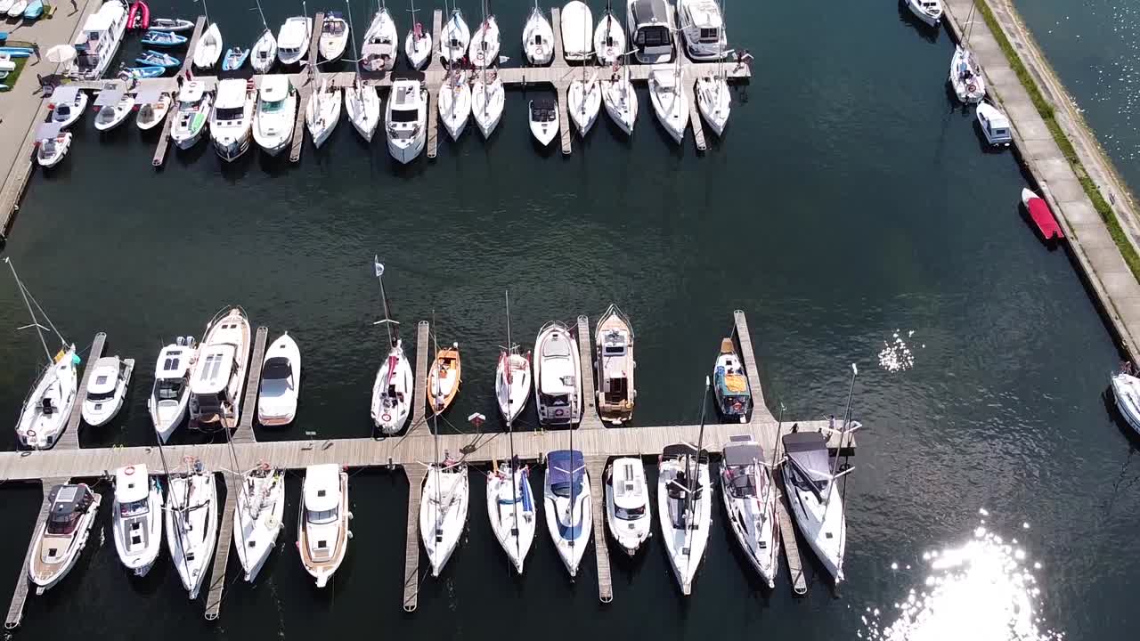 Sun reflecting on lake water in local marina with many yachts, aerial view