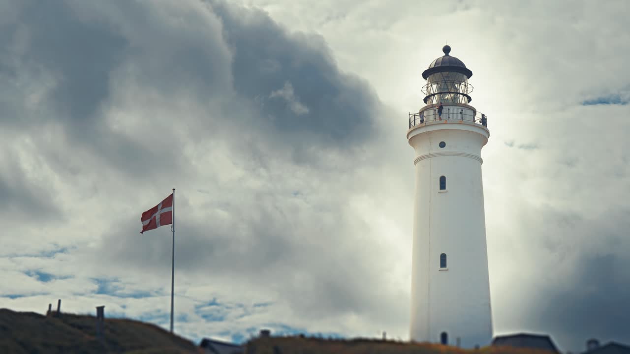Tunge stormfulde skyer flyver over fyrtårnet på den danske kyst.