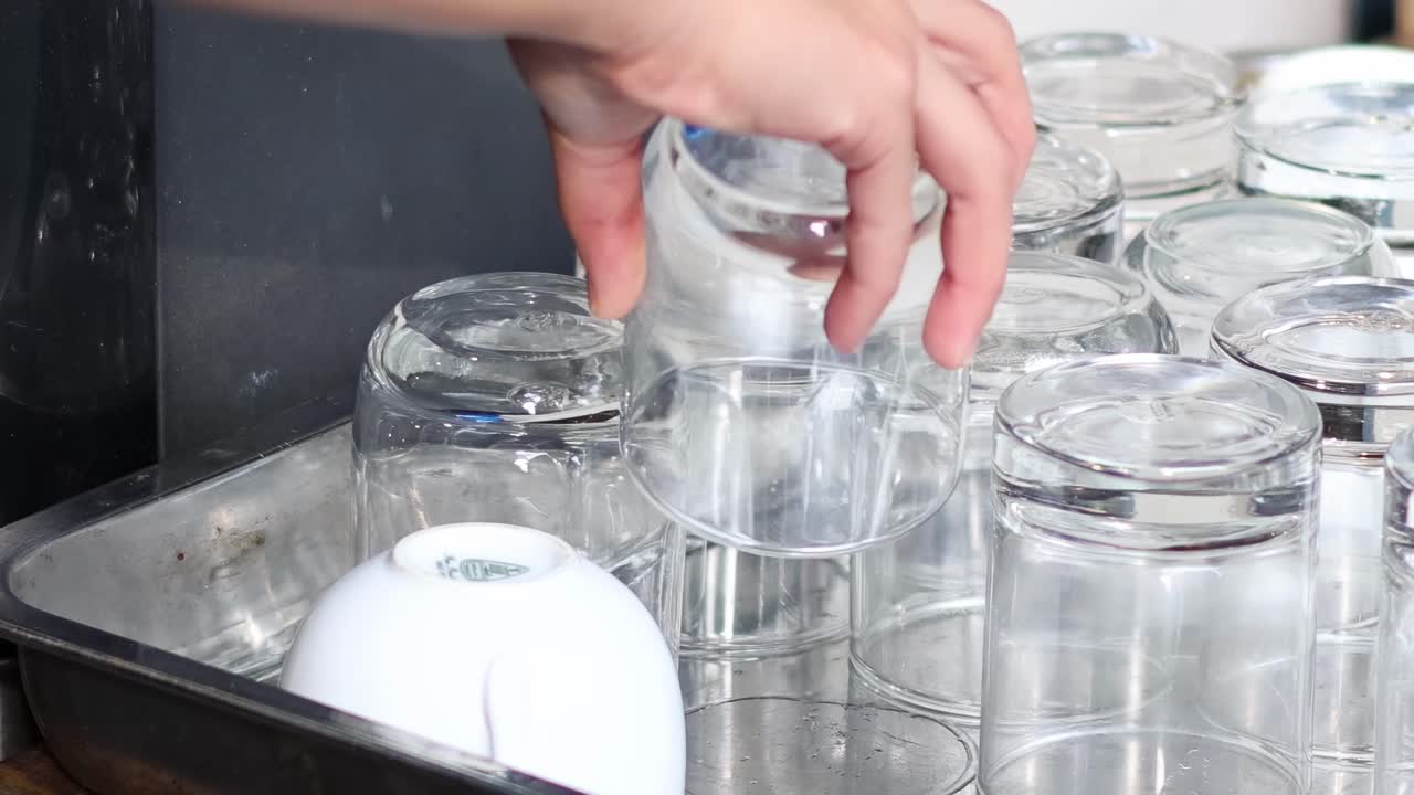 한 사람 이 트레이 에서 유리잔 을 집어 들고 있다