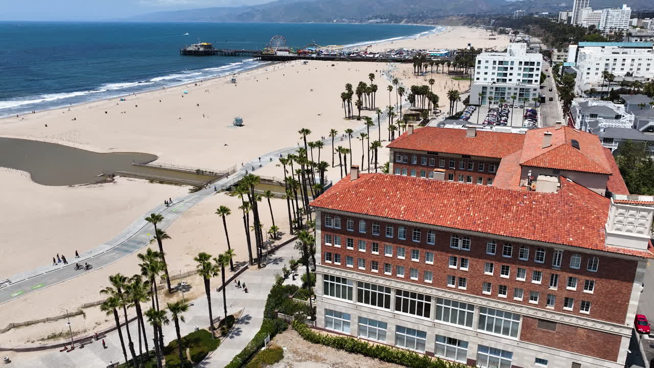 Drone circling buildings along the Boardwalk in Santa Monica, sunny day in LA
