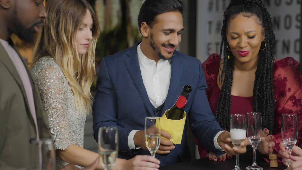tiro de seguimiento alejándose de amigos sirviendo champán durante las celebraciones de año nuevo