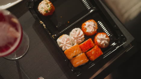 tomando un rollo de sushi con tapa de queso crema de una bandeja de plástico