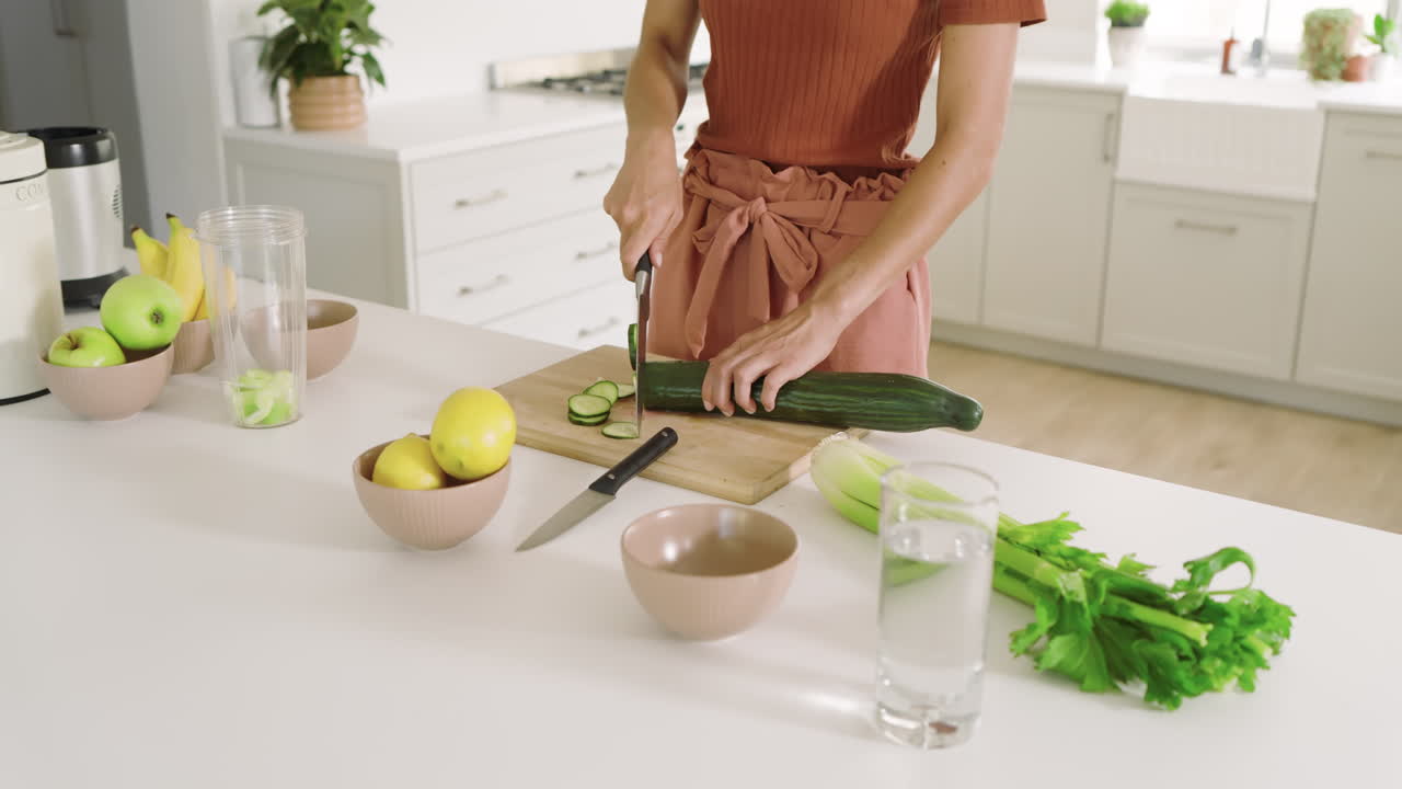 Woman preparing healthy smoothie with fresh fruits and vegetables in modern kitchen