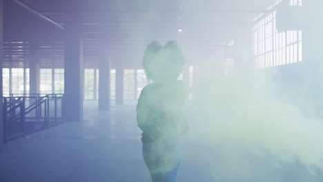 Mixed-race-woman-holding-green-flare-walking-through-empty-building