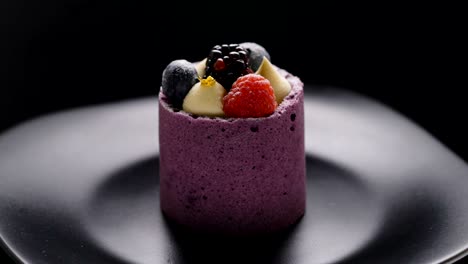 mousse dessert with fresh berries rotating on black background