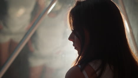 sad woman silhouette near reflective glass closeup. lady stands alone by window mirror surface at night. woman with depression at backlight