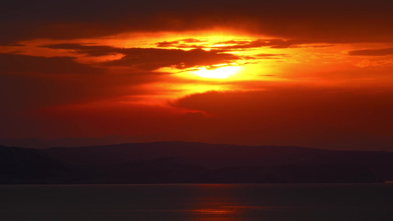 Udsigt til betagende solnedgang med intens rød og orange glød over det rolige Adriaterhav ved Senj, Kroatien