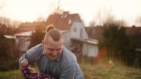 young father playing with little son outdoors