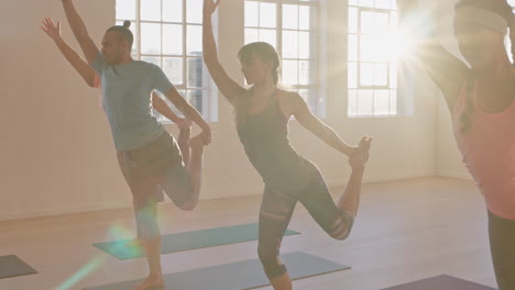 yoga class of young healthy people practicing lord of the dance pose enjoying exercising in fitness studio group meditation with instructor at sunrise