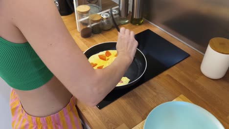 una mujer cocinando una tortilla de desayuno.