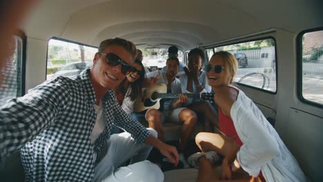 slow motion of group of young multi-ethnic friends are having fun to make a selfie or video call with a smartphone in minivan during trip on coastal road along the sea.