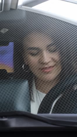 a young woman enjoys her driving experience, radiating happiness in her vehicle under clear, bright skies