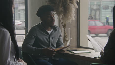 waitress takes order and serve attractive couple female waiter takes order and serve attractive couple african american man talks with woman and chooses cafe menu items multi ethnic couple on a date in modern restaurant concept of public eating