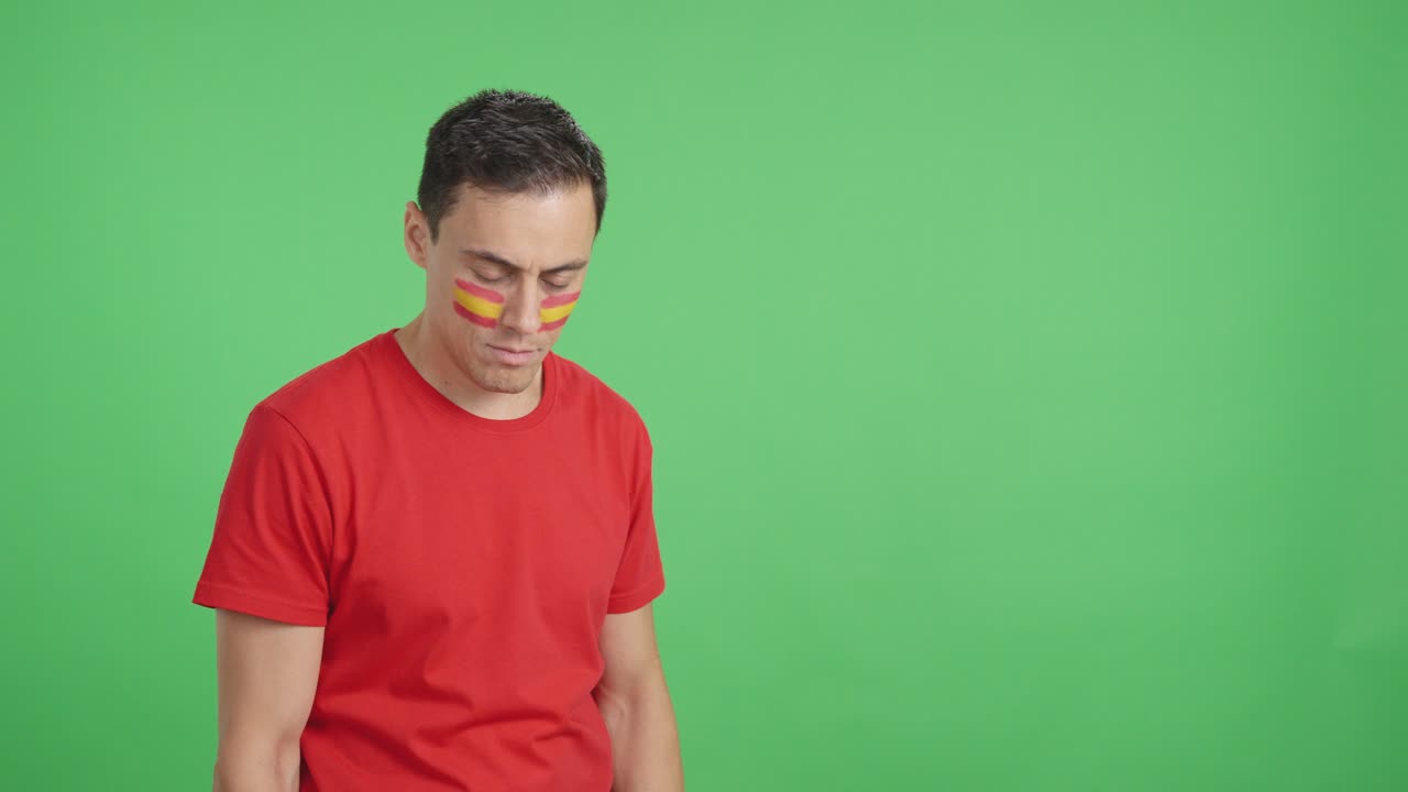 Happy man with spanish flag painted on face looking away