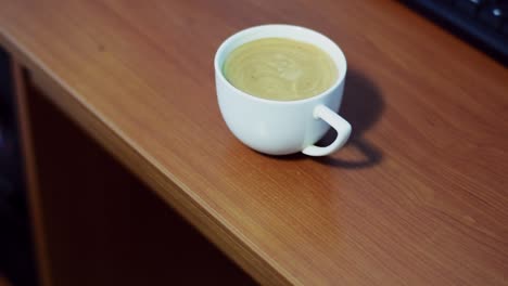 café marrón en taza blanca en el lugar de trabajo