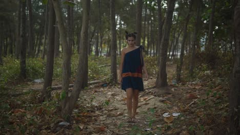 Toma-Cinematográfica-De-Una-Modelo-India-Caminando-Por-El-Bosque-Mientras-Usa-Un-Vestido-De-Moda-Sostenible-Azul,-Rojo-Y-Naranja-En-Goa,-India.