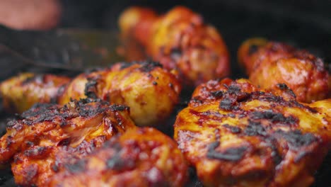 marinated chicken thighs and drumsticks cooking on smoking bbq as chef turns meat to ensure it is cooked to perfection for family dinner outside 4k