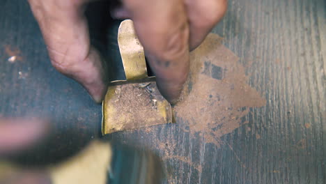 goldsmith brushes metal dust into small shovel close view