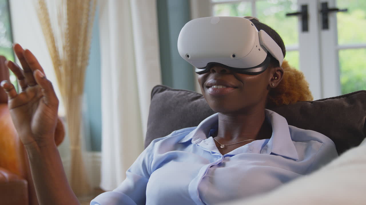 Woman Relaxing Lying On Sofa At Home Wearing VR Headset And Interacting With AR Technology