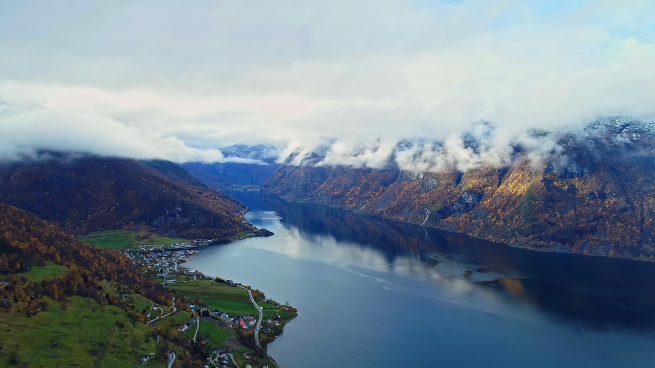 Inquadratura dall'alto di un bellissimo fiordo norvegese con la vista di una città lungo la costa in lontananza in una giornata nuvolosa
