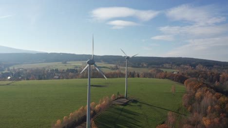 Windkraftanlagen-An-Einem-Sonnigen-Tag-In-Der-Nähe-Des-Dorfes,-Umgeben-Von-Einer-Wiese