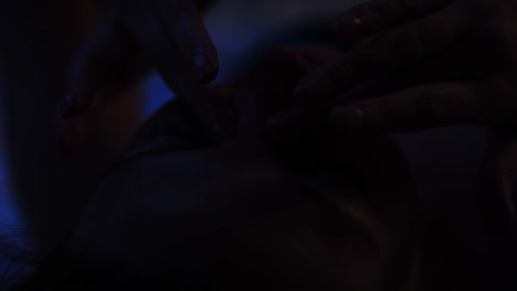 close up of a beautiful young woman lies in bed and rubs her eyes in a dark bedroom