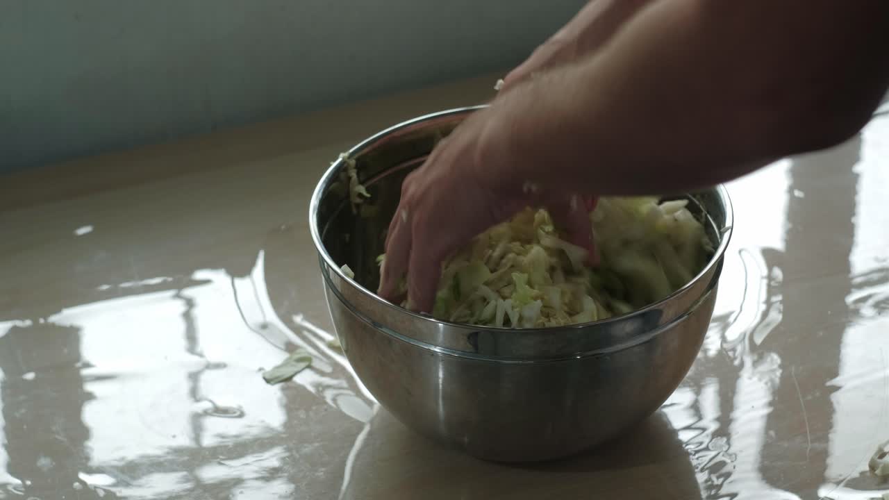 Person Mixing And Squeezing The Cabbage With Salt On Bowl - Homemade Sauerkraut. - closeup shot