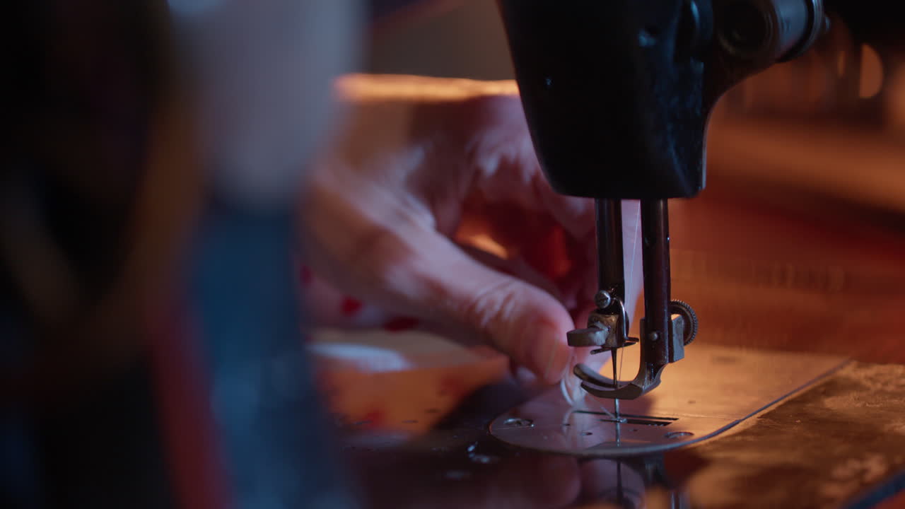 Primo piano di mani che infilano l'ago su una macchina da cucire vintage