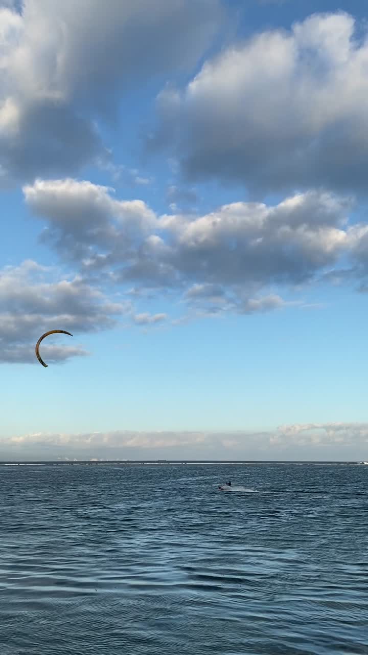 Social media style shows kitesurfer moving across deep blue ocean near Amed on eastern Bali with calm horizon, soft clouds, gentle wind and wide open seascape during peaceful afternoon light