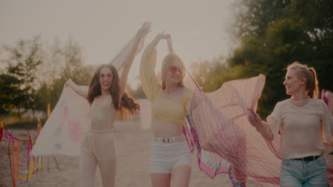 carefree young women swaying sarongs at beach