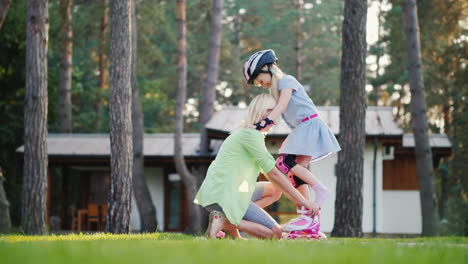 happy childhood a young mother helps to put roller skates on her daughter in the backyard of their h