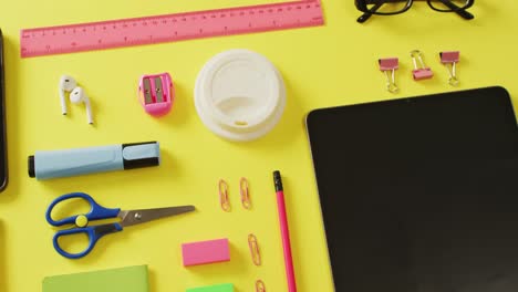 video of diverse office tools, tablet and smartphone with copy space on yellow background