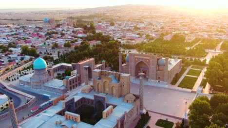 vista aérea de las madrazas en registan con la estatua conmemorativa de islam karimov y la ciudad durante la hora dorada en samarcanda, uzbekistán