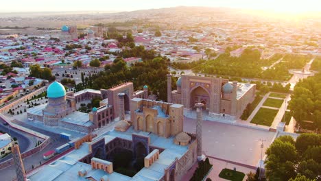 aerial view of madrasahs in registan with islam karimov memorial statue and city during golden hour in samarkand, uzbekistan