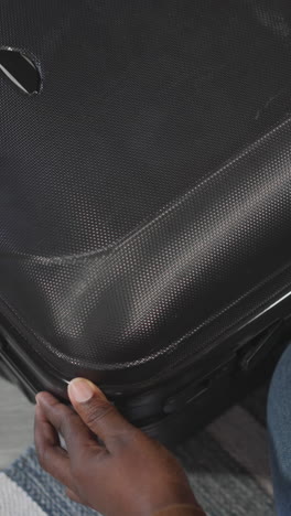 african american woman closes big black suitcase with clothes prepared for summer vacation. female person gets ready for flight abroad closeup