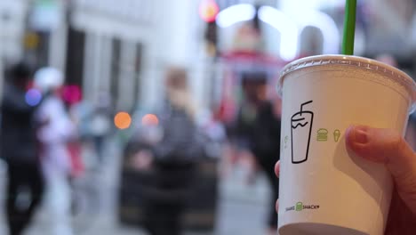 hand holding coffee cup in busy london street