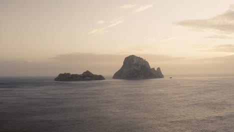 Establishing-Aerial-Rock-Formation-In-Es-Vedra-Island-On-A-Hazy-Sunset-Evening,-Ibiza-Spain