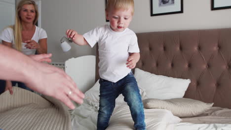 happy family playing to pillows fight on bed at home