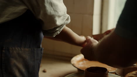 unrecognized woman washing hands in pottery. man cleaning woman hands in studio