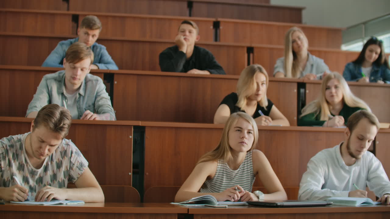 en el aula estudiantes multiétnicos escuchando a un conferenciante y escribiendo en cuadernos. jóvenes inteligentes estudian en la universidad.