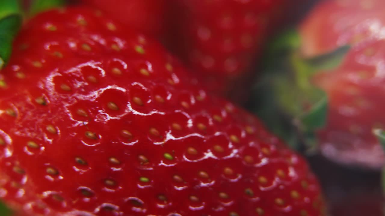 video macro dettagliato di un mucchio di fragole, fragole rosse, frutta verde, piccoli semi, su un supporto di riflessione rotante, luce di studio, 4k