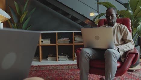 two male colleagues working on laptops and having talk in cozy office