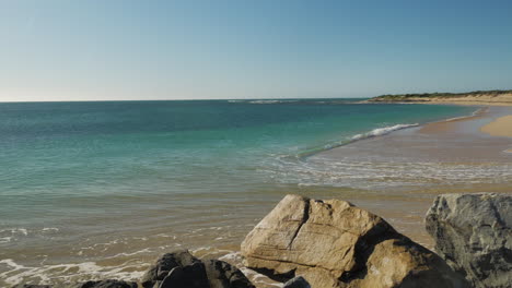 Small-wave-pushing-high-up-onto-beautiful-deserted-beach,-panning-shot