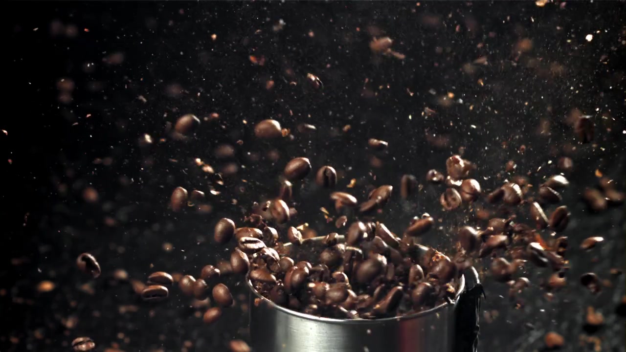 Chicchi di caffè tostati che cadono in un macinacaffè al rallentatore