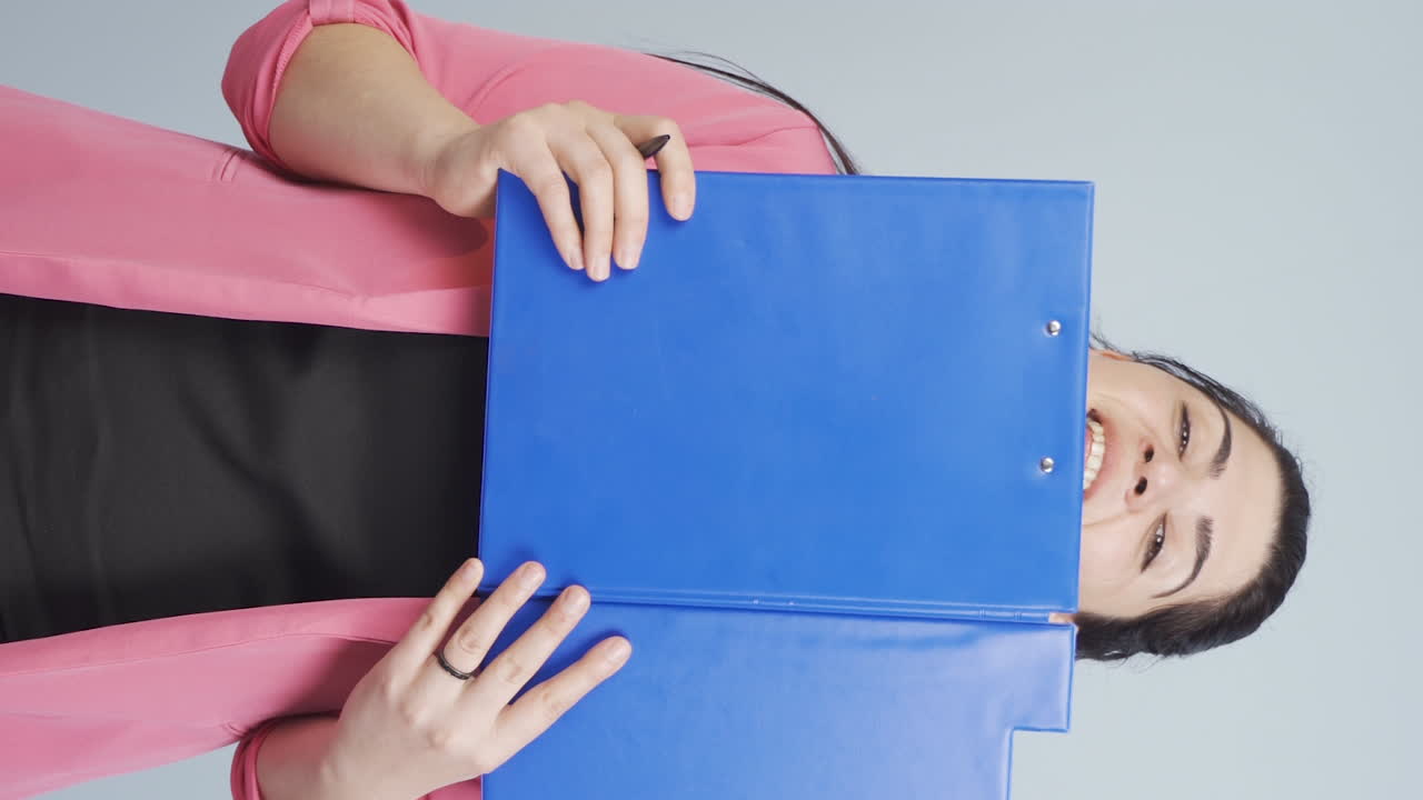 Vertikální video: Podnikatelka se dívá zpoza dokumentů.