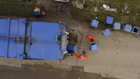 fotografía aérea de arriba hacia abajo de un camión de basura recogiendo contenedores de basura