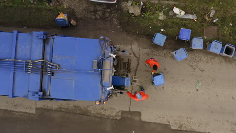 aerial top down ascending shot of garbage truck collecting trash bins